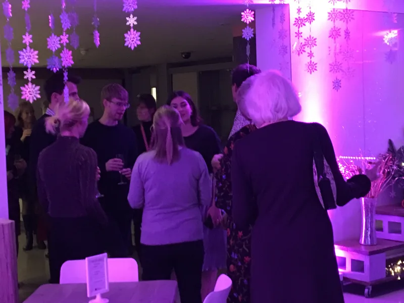A festively decorated event venue with hanging snowflake decorations and ambient lighting, set up for an evening Christmas party