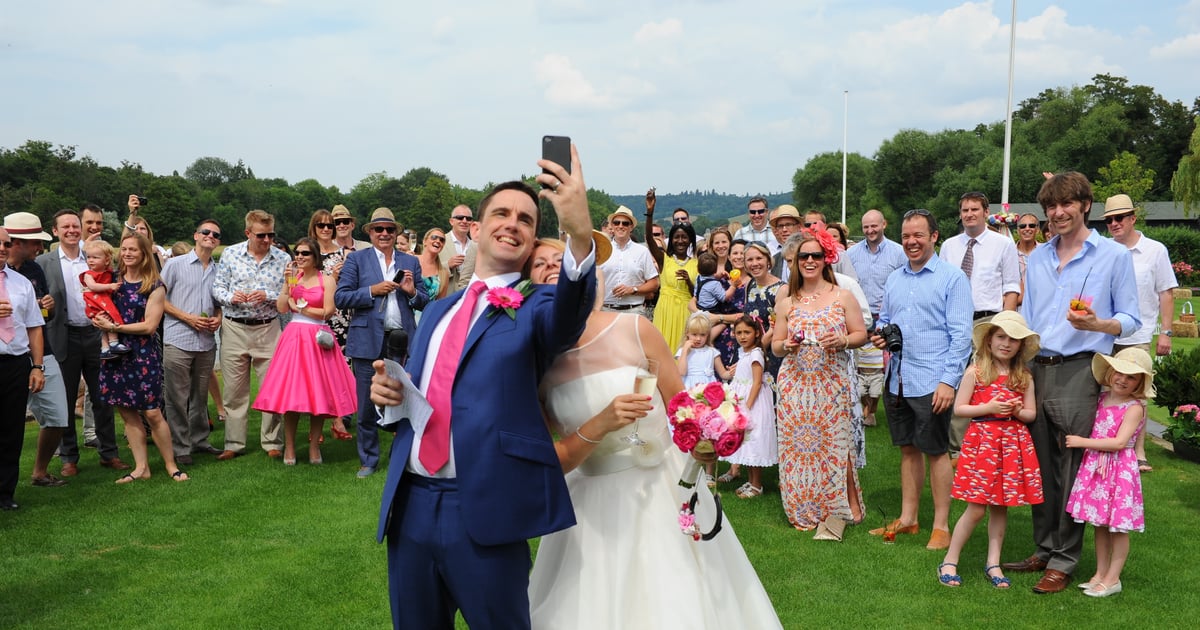 Wedding guests from different groups laughing together at a reception table