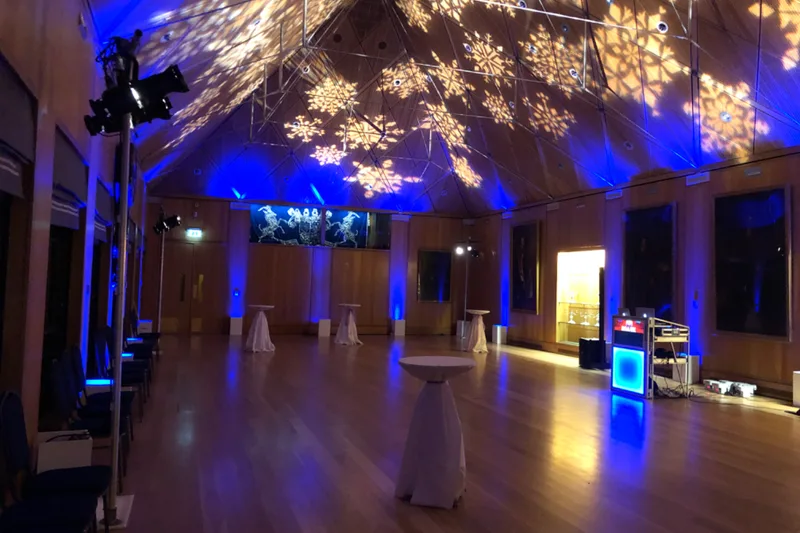 An empty dancefloor lit with projected snowflake patterns and festive lighting, set up ahead of an office Christmas party