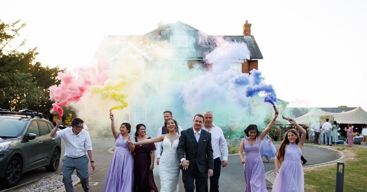 Wedding party celebrating with coloured smoke outside the teepee marquee at The Lodge, Duxford