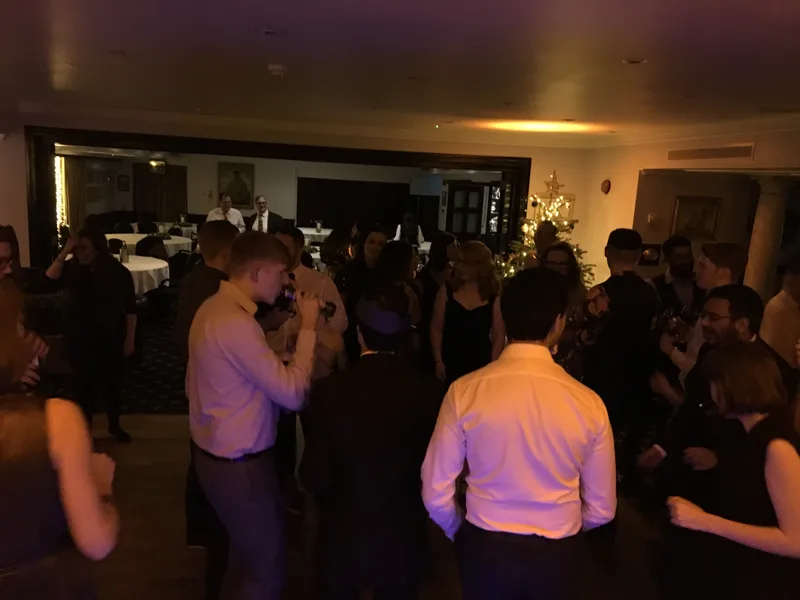 Office colleagues dancing and celebrating around a decorated Christmas tree at a company Christmas party
