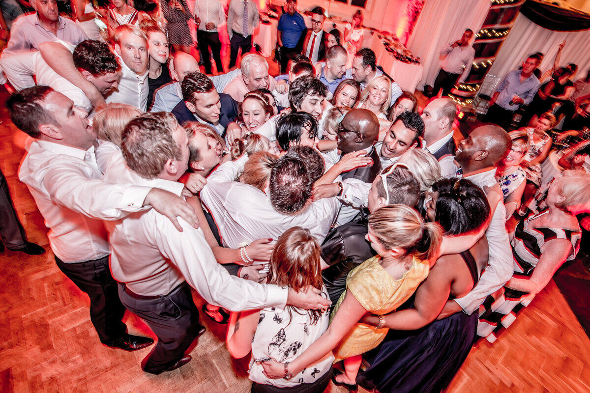 Wedding guests with their arms around each other in a big circle on the dance floor