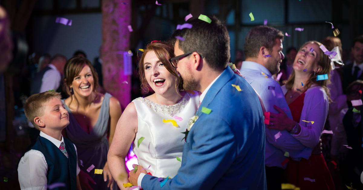 Couple dancing through confetti with laughter at their wedding