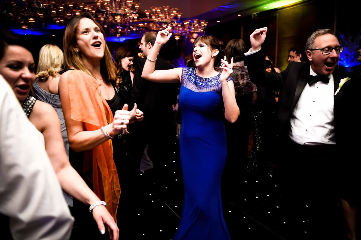 Guests dancing and singing on a packed wedding dance floor