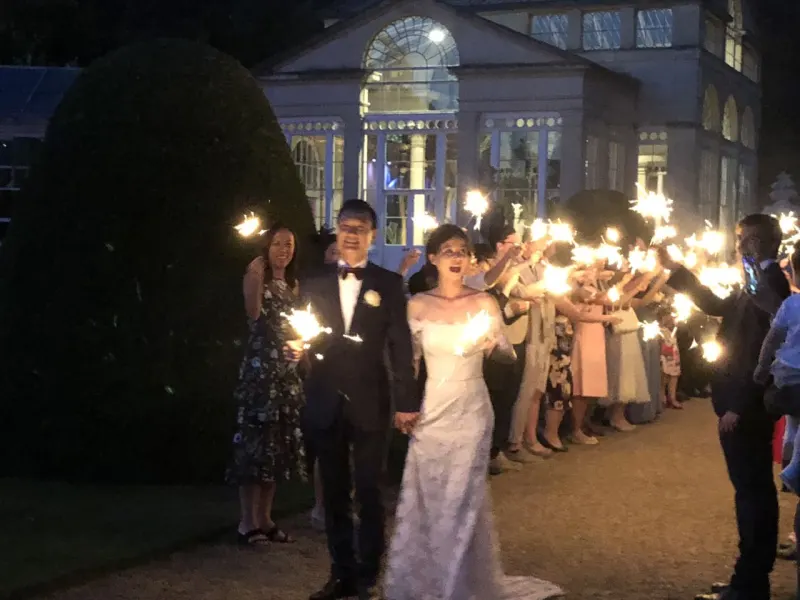 A bride and groom walking between guests holding sparklers at a wedding send-off